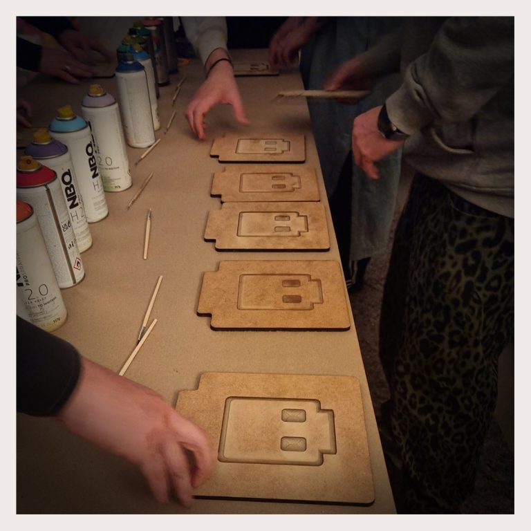 OOYAH-Workshop - arbeiten an Holzplatten, umgeben von Spraydosen und Werkzeugen.